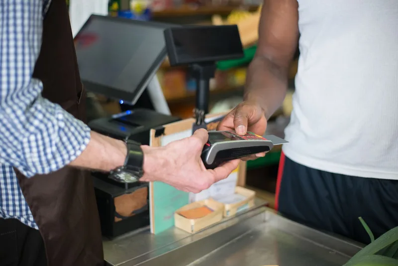 Customer making a payment at a store checkout counter using a card reader