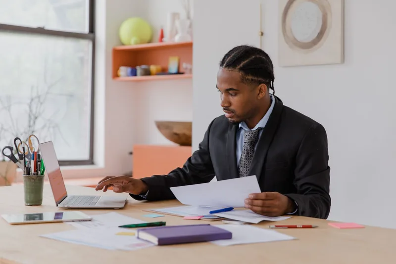 Business owner reviewing payment gateway documents and laptop in an office setting