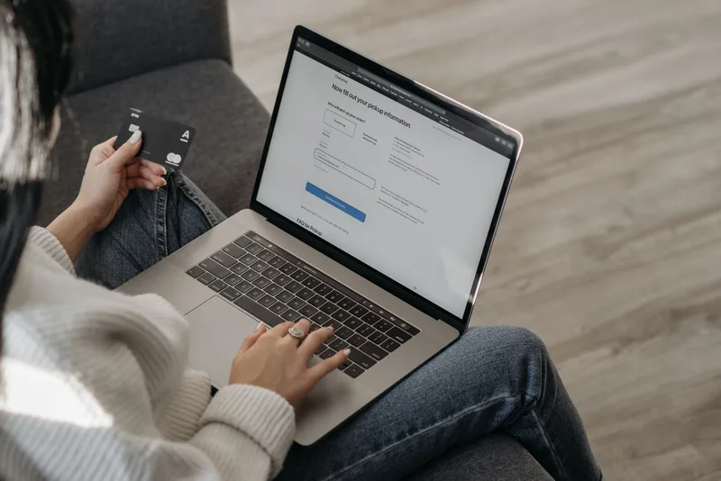 Person reviewing payment gateway options on a laptop with a credit card in hand