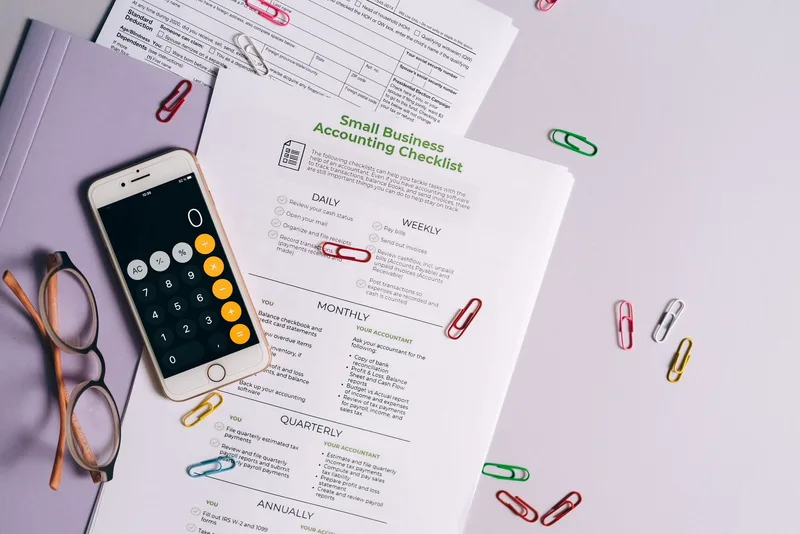 Top view of accounting essentials including smartphone, eyeglasses, and paperwork